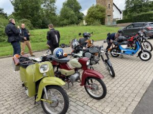 Mopeds au einem Parkplatz mit sich unterhaltenden Fahrern.