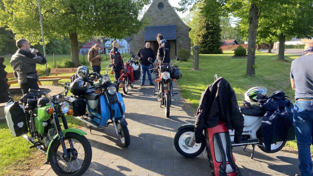 Simsommopeds vor einer Kapelle