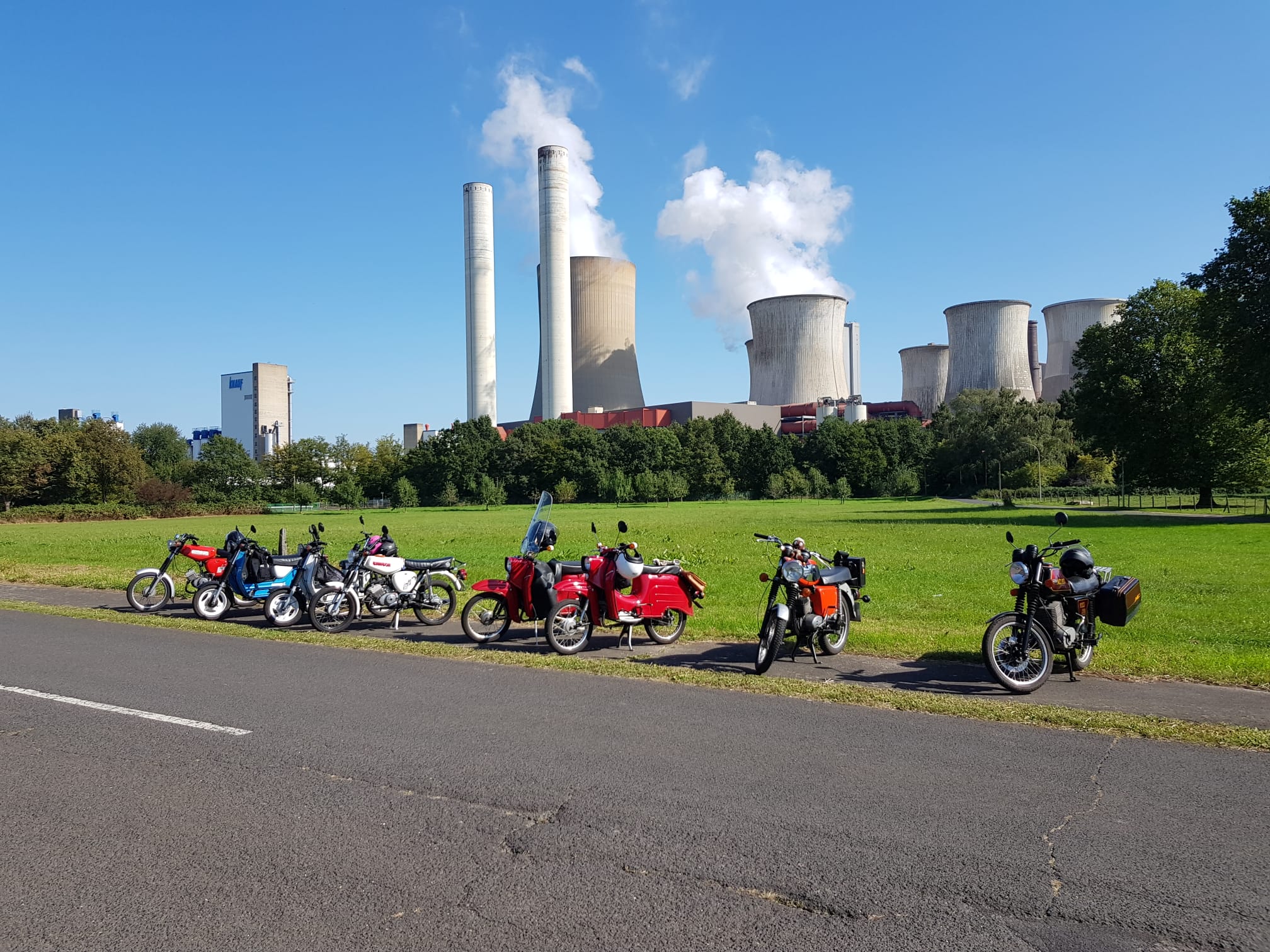 Mehrere Mopeds vor einem Kraftwerk