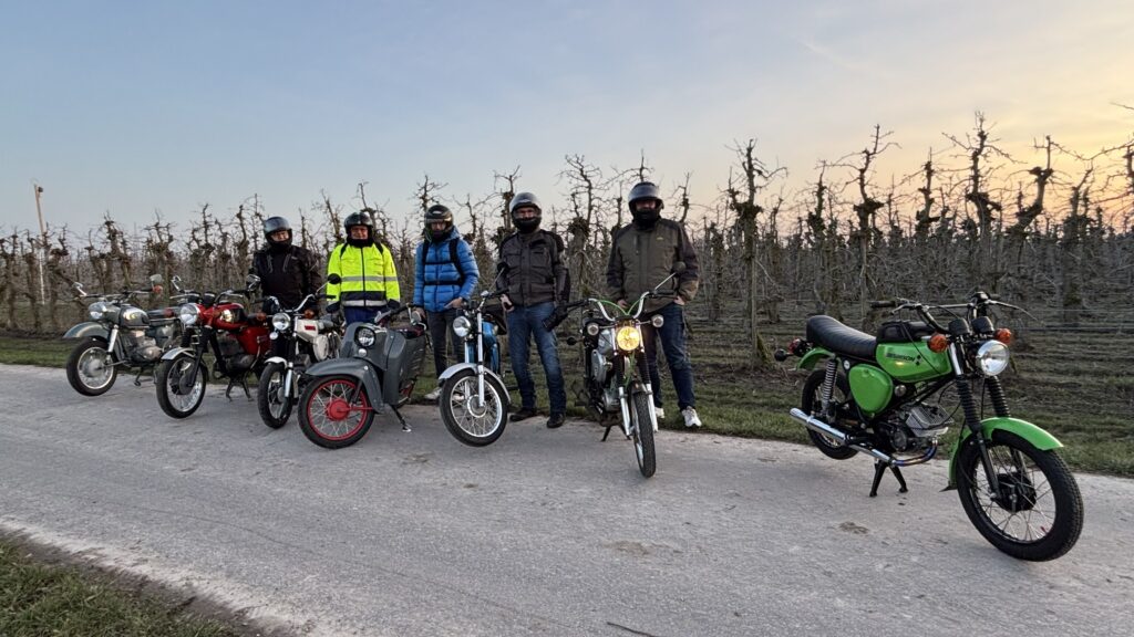 mehrer Mopeds vor einer Apfelplantage